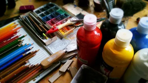 Paint bottles, colored pencils, paper, paint brushes, and other art supplies