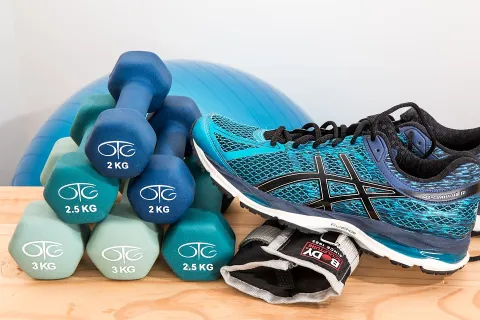 Sets of different colored dumbbells, blue tennis shoes, and a blue balance ball