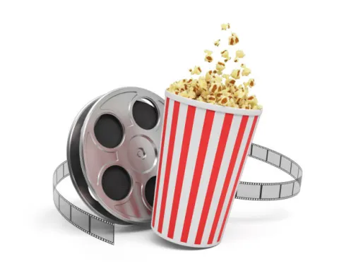 Black movie reel open and a red and white striped cup of popcorn while popcorn is spilling out of the top of the cup