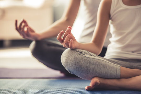 Two people in a yoga pose while sitting on yoga mats on the floor