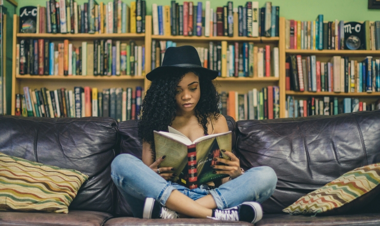 Teen reading book on couch